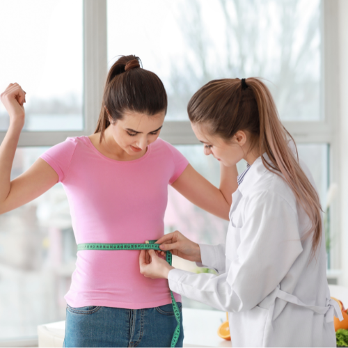 Provider measuring waist of patient with weight loss success